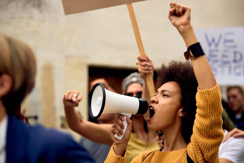 Young,African,American,Woman,With,Raised,Fist,Shouting,Through,Megaphone
