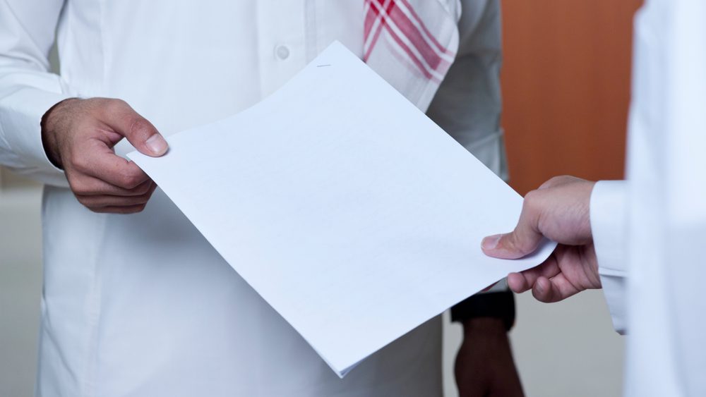 Ärztin übergibt Dokumente an Patienten.