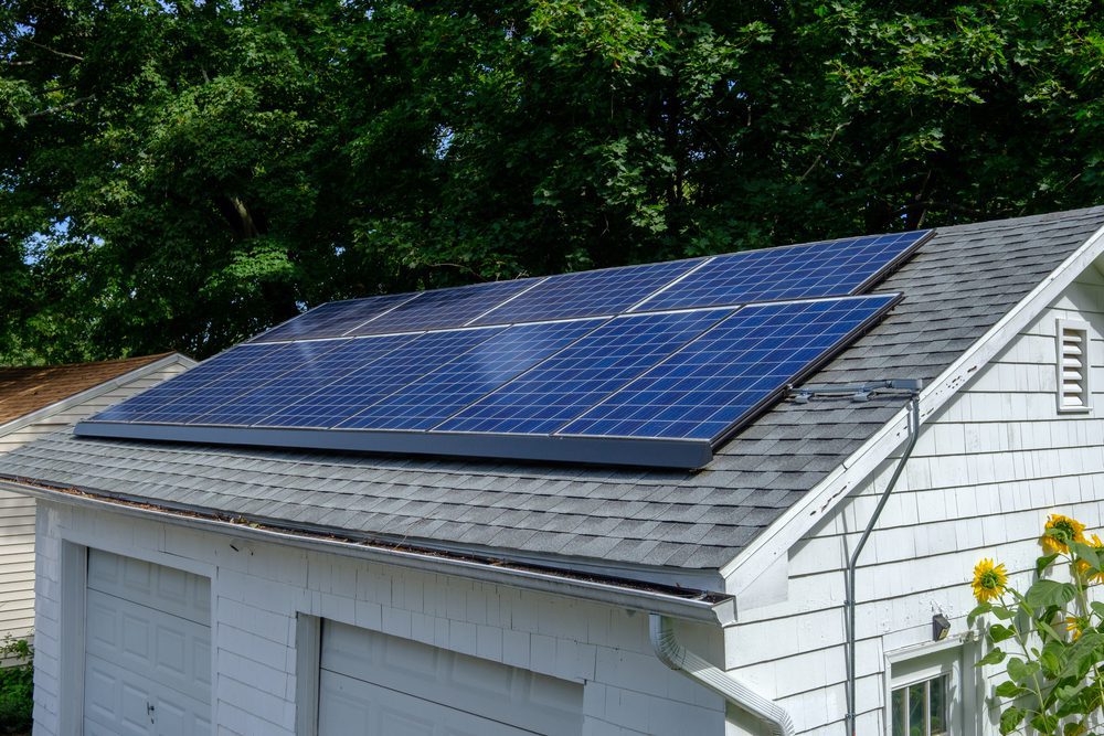Solarpaneele auf Hausdach mit Bäumen im Hintergrund.
