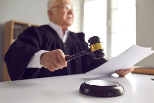 Richter mit Hammer und Dokument im Gerichtssaal.