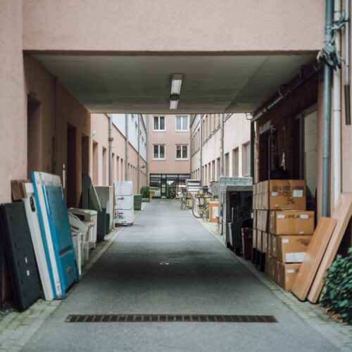 Gewerblich genutzte Durchfahrt zwischen Häusern mit gelagertem Material