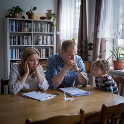 Familie am Esstisch bespricht besorgt Masernimpfnachweis mit Dokumenten und Impfheft.